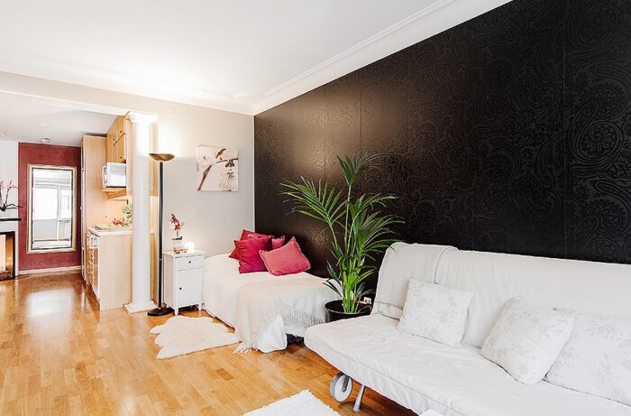 czarna ściana w salonie,salon z aneksem kuchennym,otwartry salon,salon w szarym kolorze,antyczne filary w salonie,ozdobne filary w salonie,otwarta zabudowa salonu,jak urządzić małe mieszkanie,mini mieszkania,jak urządzić salon w kawalercr,salon dla singla,miks stylów,mieszanka stylów w salonie