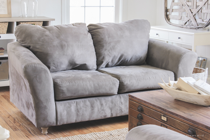 Szara wygodna sofa w salonie dobrze wpisuje się w klasyczny styl wystroju wnętrza. Drewniany stolik kawowy zapewnia...