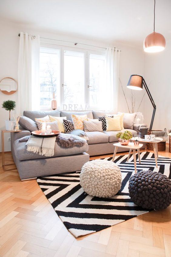 W wysokim salonie uwagę przykuwa do siebie przede wszystkim wzorzysty dywan w biało-czarnej kolorystyce. Szara sofa...