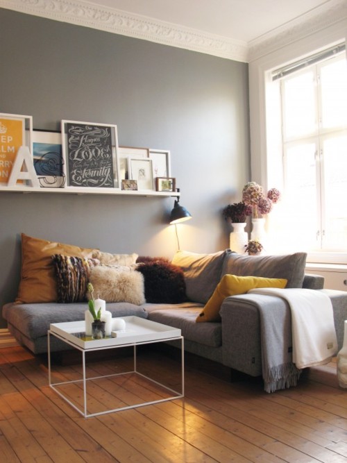 szare ściany,szara sofa,białe dekoracje,żółte poduszki,żółte obrazy,brązowe dodatki, iżółte dodatki,
