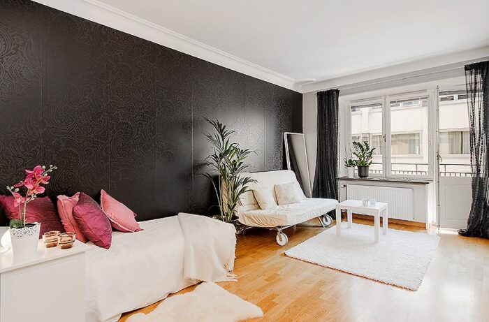 czarna ściana,salon z aneksem kuchennym,otwartry salon,salon w szarym kolorze,antyczne filary w salonie,ozdobne filary w salonie,otwarta zabudowa salonu,jak urządzić małe mieszkanie,mini mieszkania,jak urządzić salon w kawalercr,salon dla singla,miks stylów,mieszanka stylów w salonie