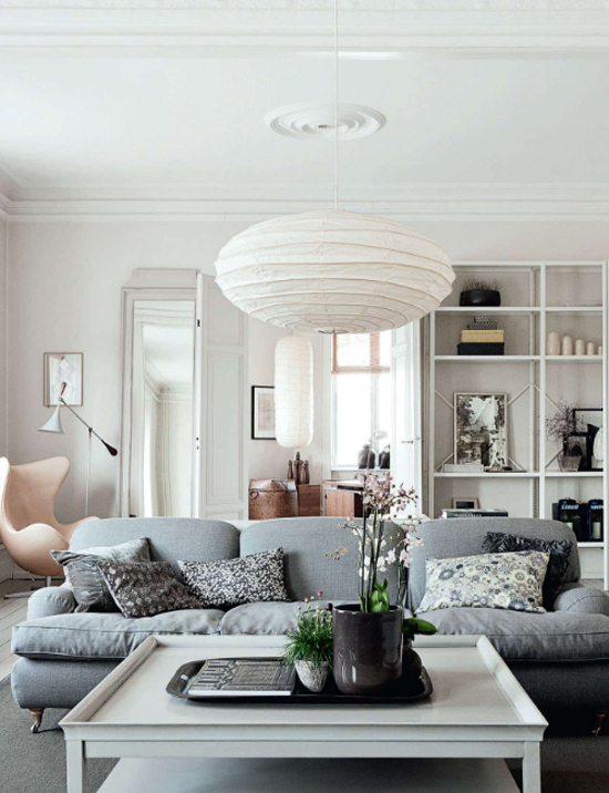 stolik taca przed sofą,szara sofa w salonie,otwarte półki na ścianie w salonie,skandynawski salon,aranżacja skandynawskiego salonu,ceramiczny piec w salonie,co postawić z boku kanapy,otwarta szafka z półkamin przy sofie,białe wnętrza w stylu skandynawskim,galeria fotografii i grafik w salonie na ścianie,jak skomponować domową galerię na ścianach